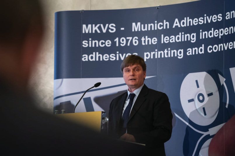 Man in a suit at a lectern.