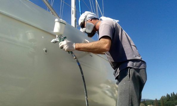 Man with protective mask paints ship.