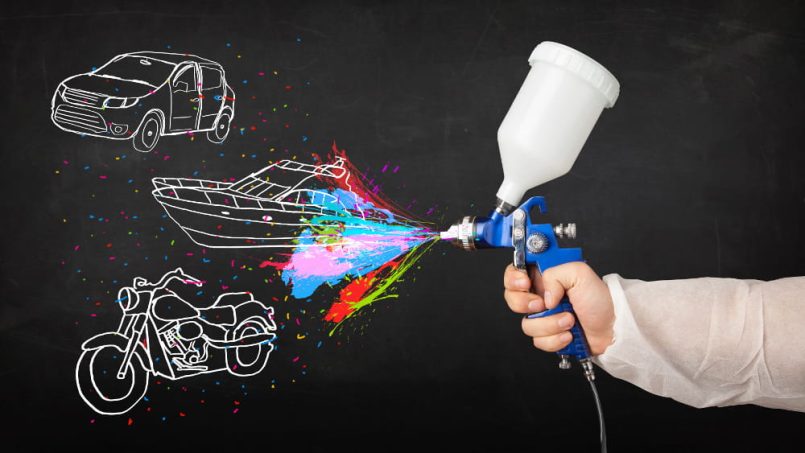 Paint spray gun in front of chalk drawings of car