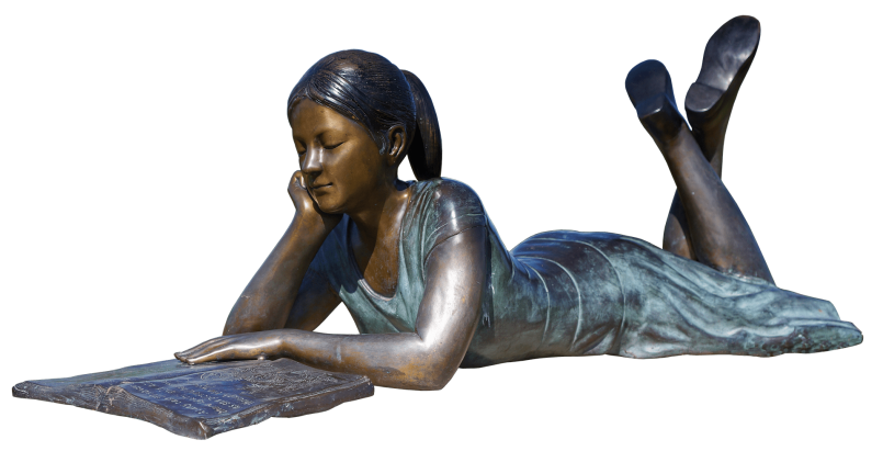 Bronze statue of a girl lying on her belly reading in an open book.