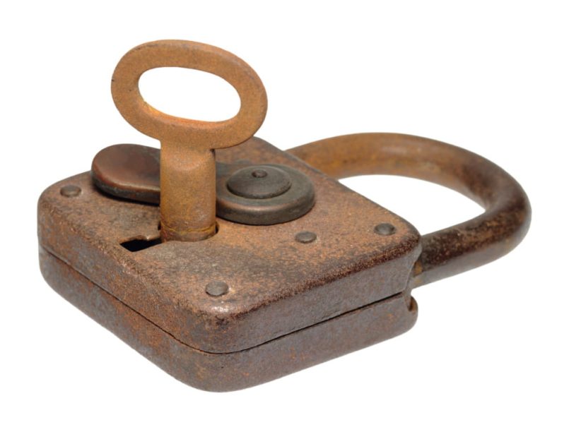 Rusty padlock with a rusted key in it.