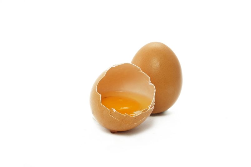 Brown egg shell with egg yolk in it.