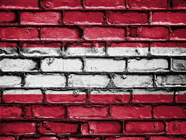 The Austrian flag with paint applied to a brick wall.