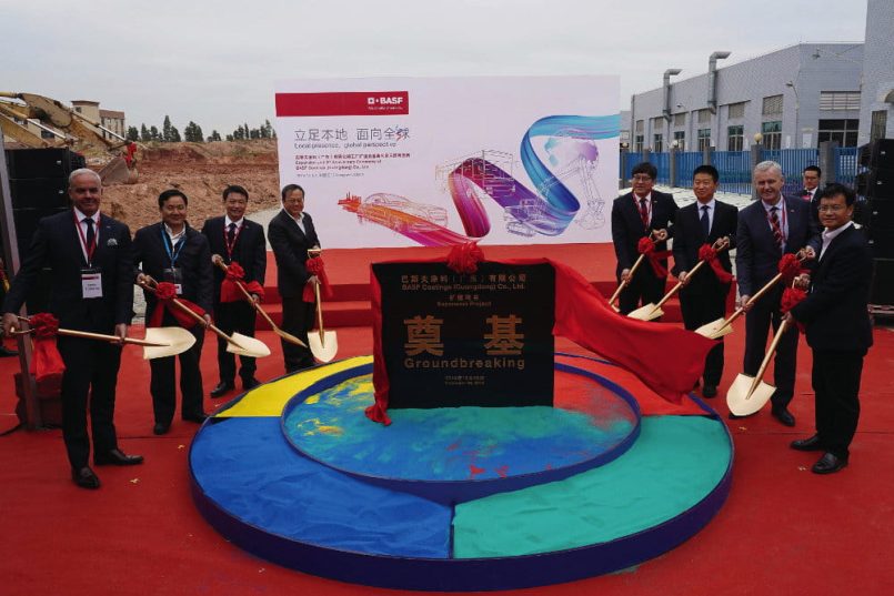 Men with golden spades stand around a box filled with different coloured powders.