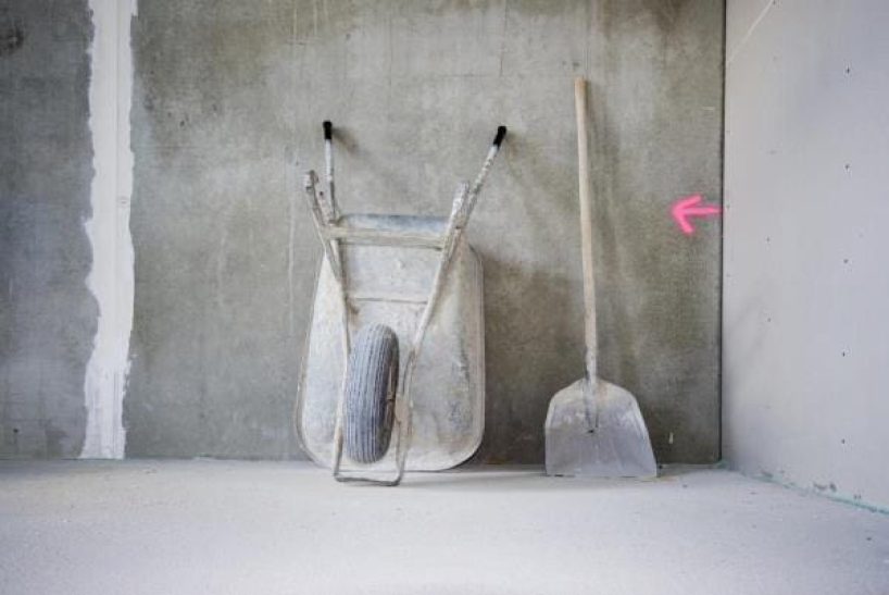 A wheelbarrow in front of a concrete wall as a symbolic image.