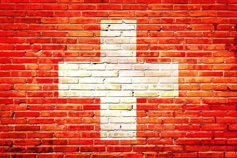 The Swiss flag painted on a brick wall as a symbolic image.