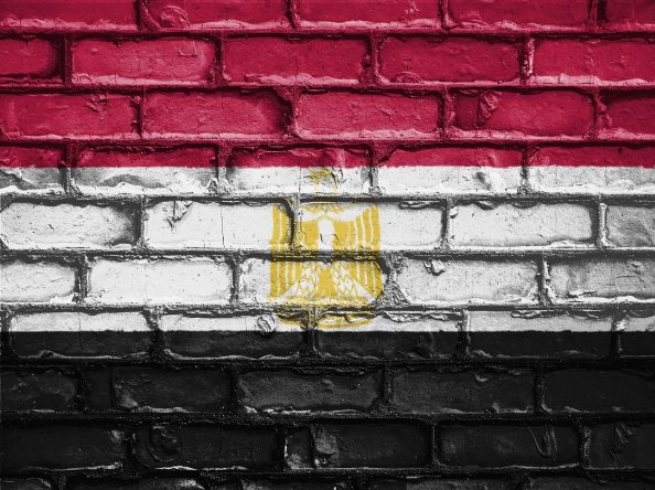 The Egyptian flag symbolically applied with paint on a brick wall.