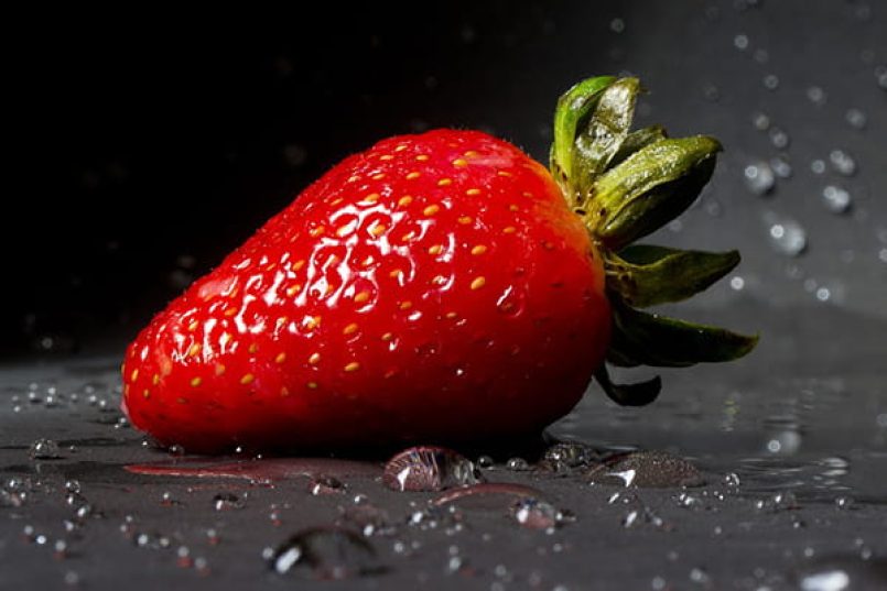 A strawberry against a dark background.