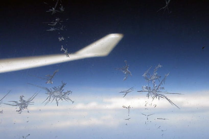 The wingtip of an aircraft photographed through a window with adhering ice crystals.