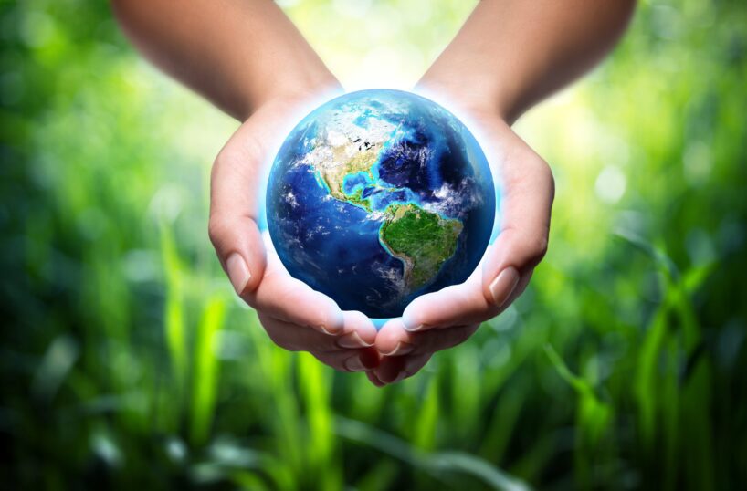 The earth in hands held against a green background.