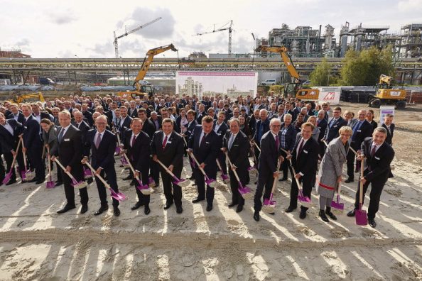 Men and women with spades in front of a construction site.