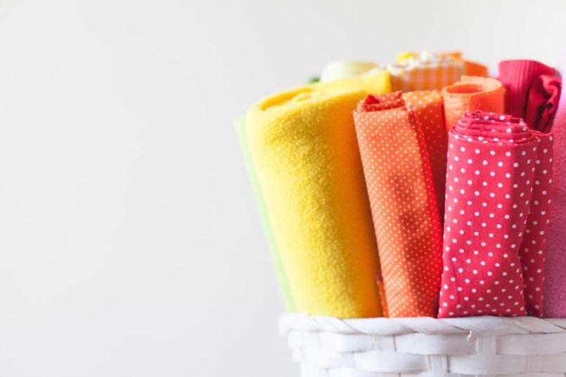 Basket with rolled up cotton cloths in different colours.