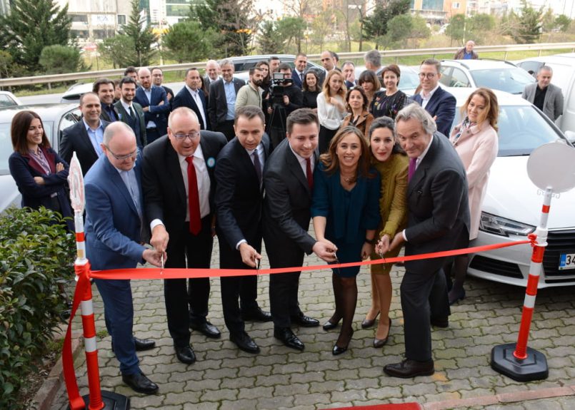 Men and women cut a red ribbon with scissors.