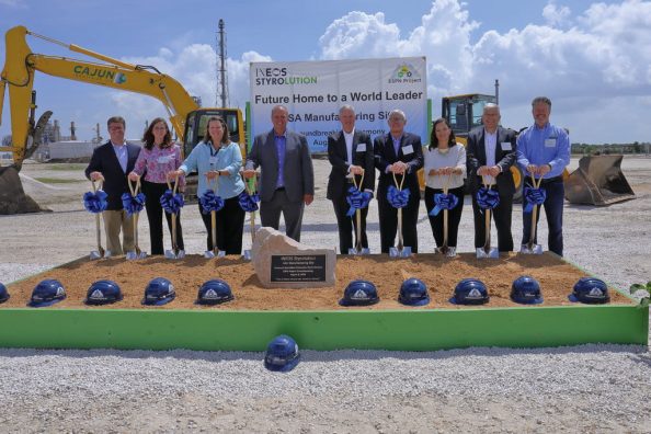 Men and women with decorated spades in front of a sandpit