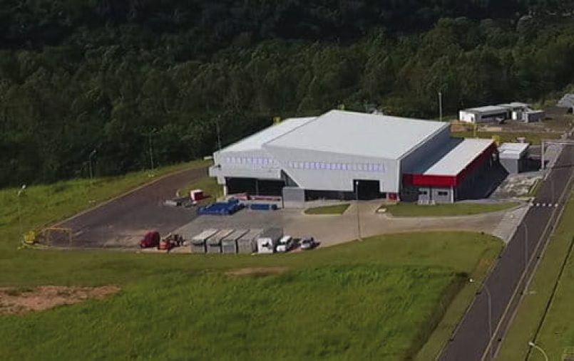 Factory site on a green meadow with trees behind it.