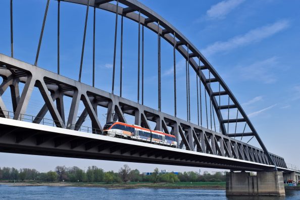 Train passes over a bridge that crosses a river.