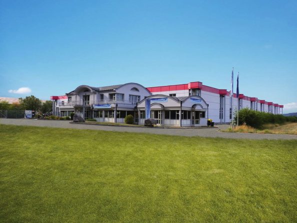 Company building with the company logo of Pigment Solution on a green meadow.