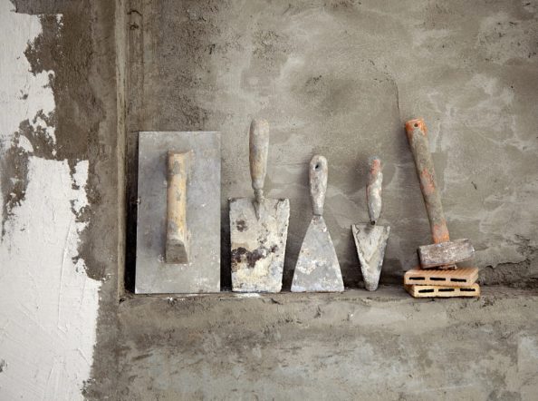 Mason's trowels lean against a wall.