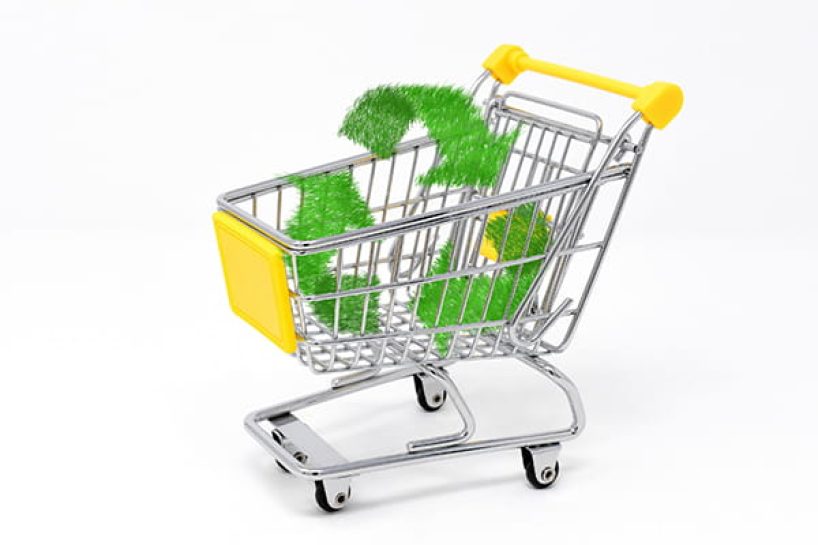 A green recycling symbol in a shopping trolley with yellow handles.