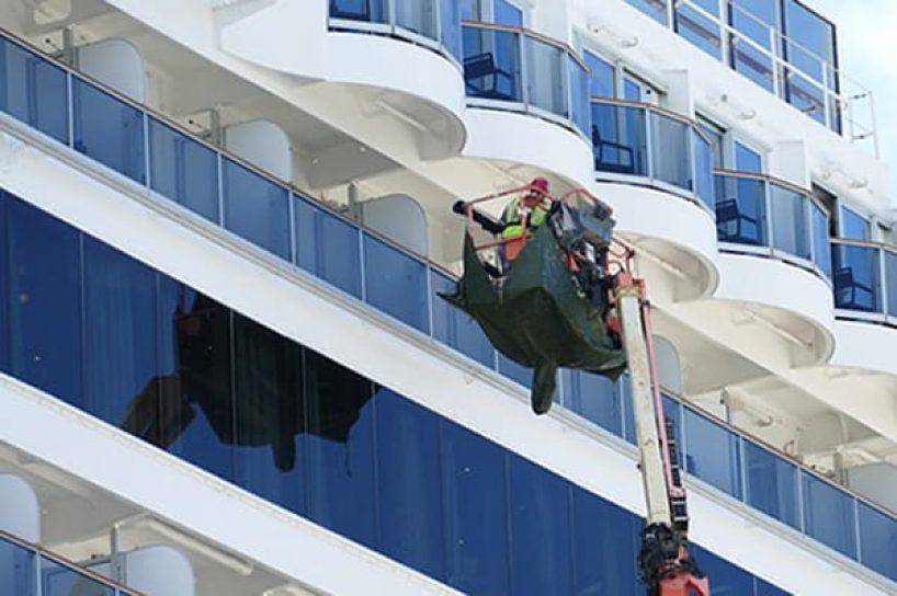 A cruise ship is cleaned from the outside with high pressure.