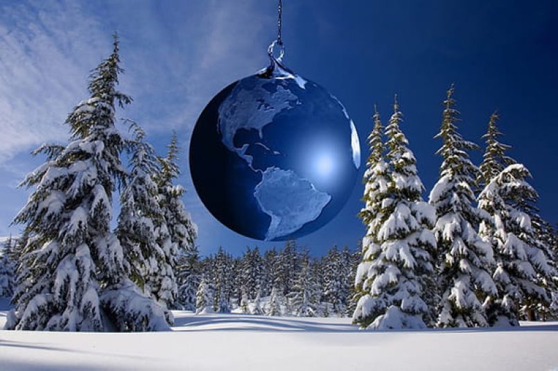 A Christmas tree ball as an earth ball in a wintry fir forest.