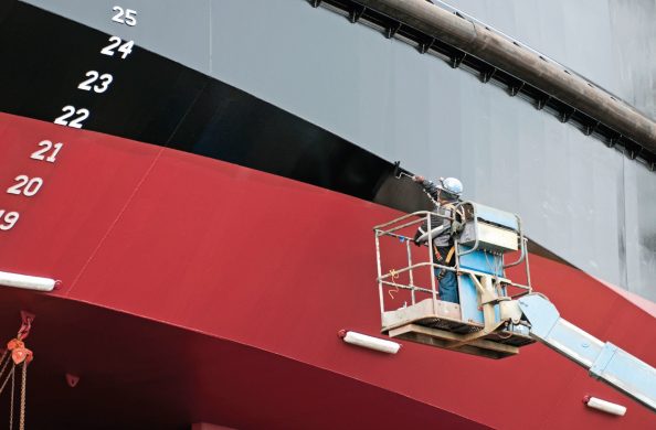 A person on a facade access system paints the outer facade of a building.