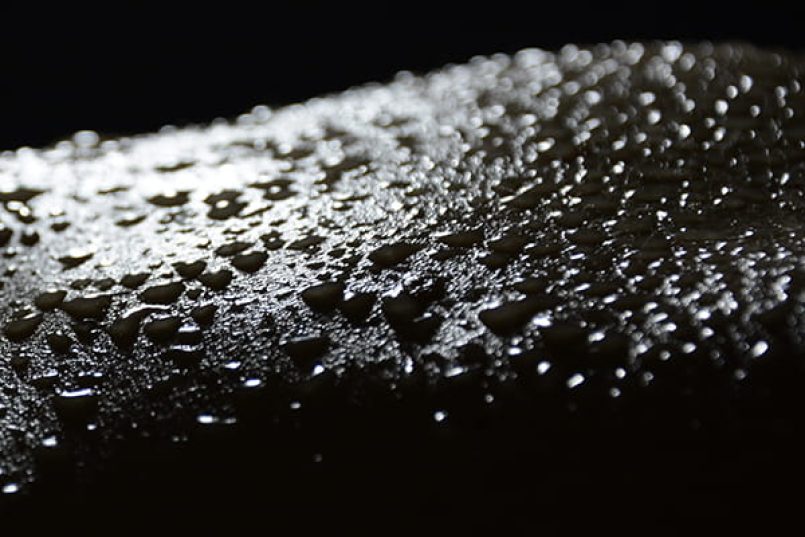 A monochrome image of water drops on human skin.