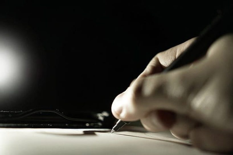 A close-up of a hand signing a document.