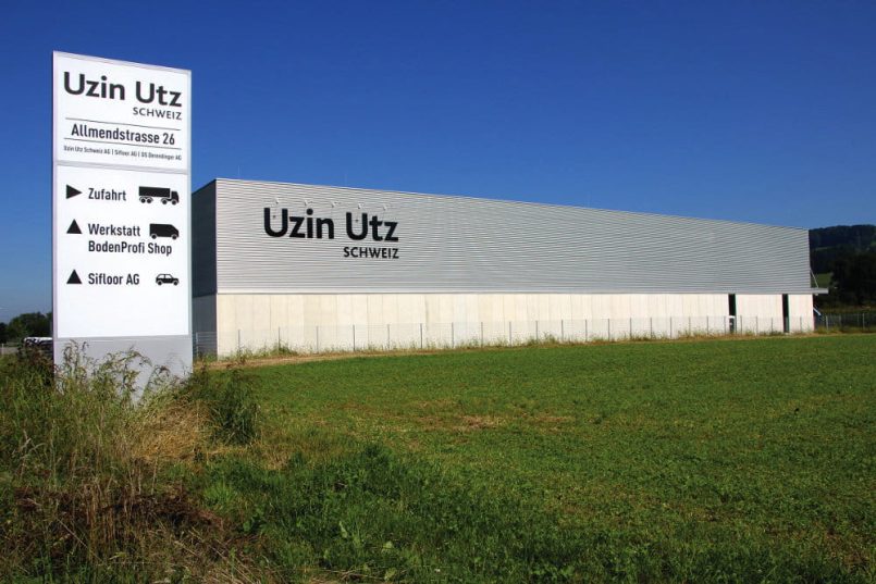 Signpost next to a flat roof building with the inscription of the company name Uzin Utz.