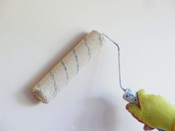 Paint is applied to a wall using a roller.